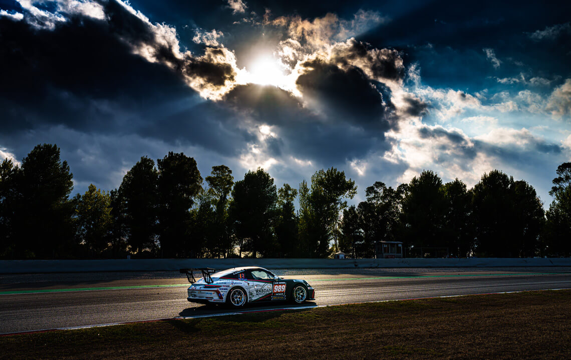 voiture de course au couché du soleil sur un circuit.