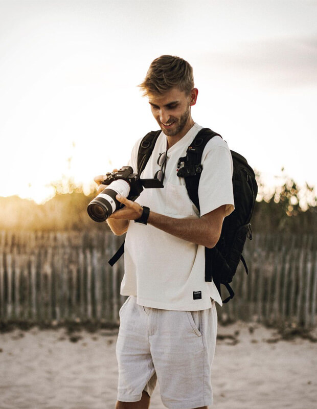 Alex Jackson homme debout avec un appareil photo à la plage