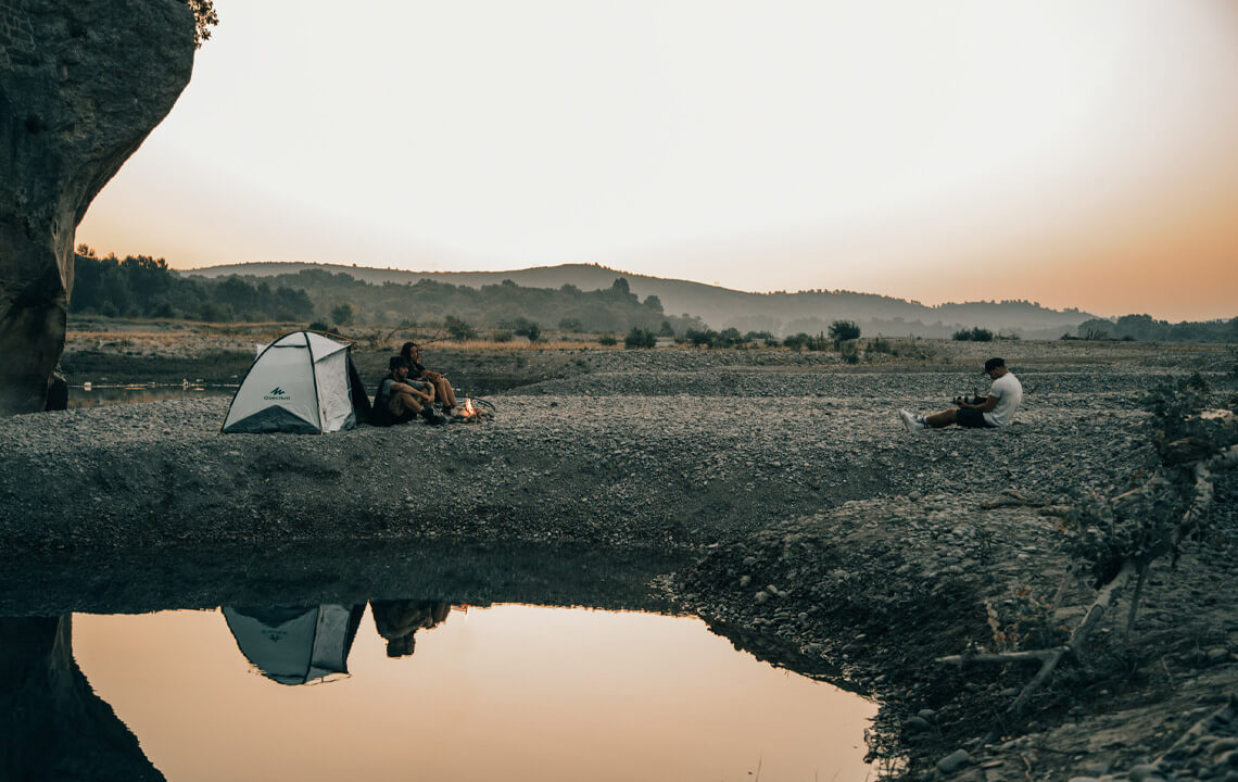 un couple devant une tente au couché du soleil