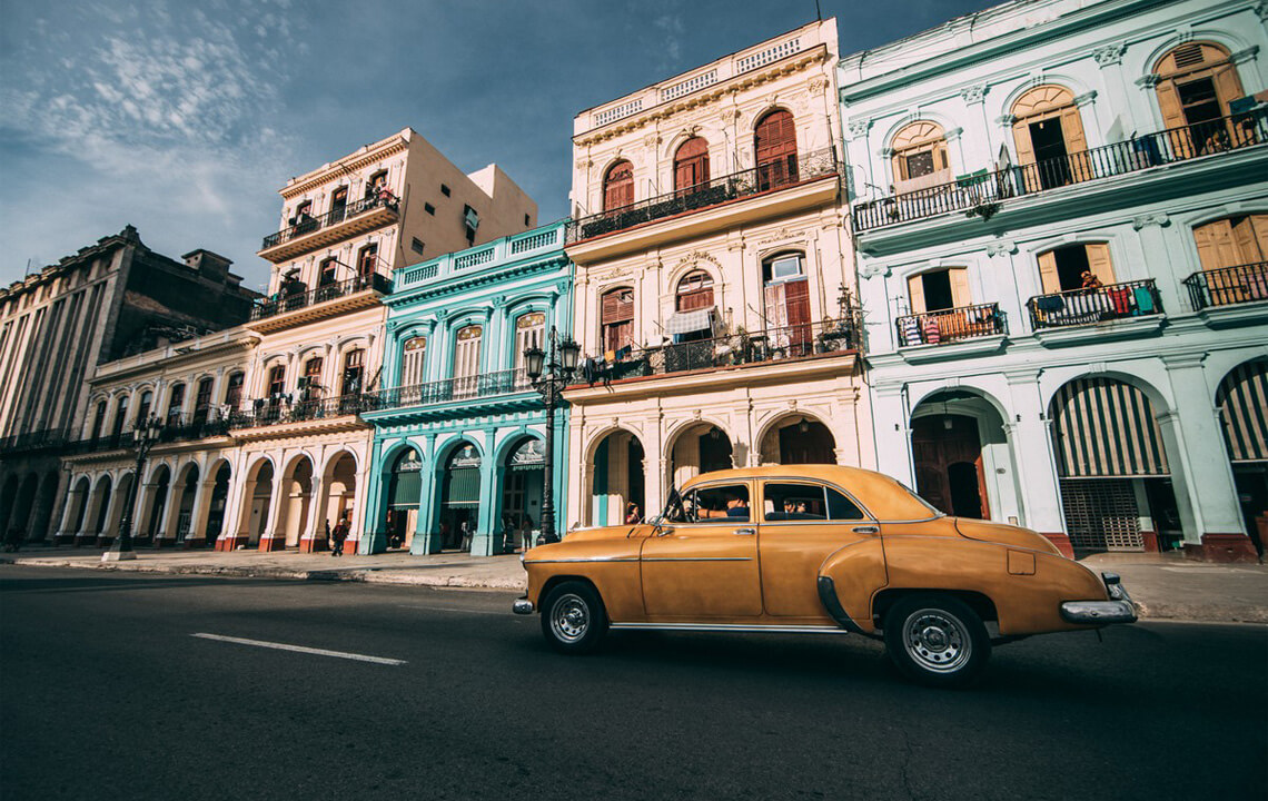 voiture à Cuba devant des maisons de couleurs