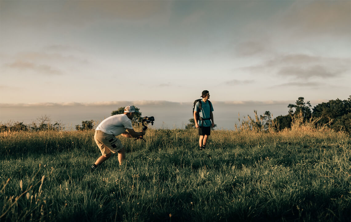 Vidéaste qui film un homme debout dans l'herbe